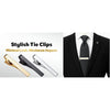 A close-up of a gold elegant men's tie clip resting on a white shirt and black suit jacket.