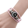 A pink braided bracelet with silver and black charms featuring a crescent moon and star design.