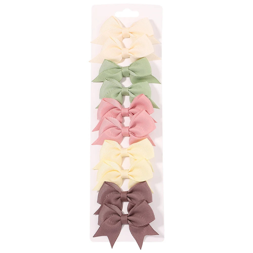 Un juego de pinzas para el pelo con forma de lazo en colores sólidos: amarillo pálido, verde menta, rosa y malva.