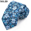 Une cravate à motif floral bleu foncé pliée et présentée sur un fond blanc.