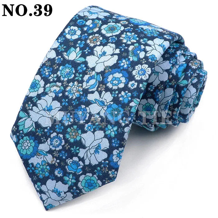 Une cravate à motif floral bleu foncé pliée et présentée sur un fond blanc.