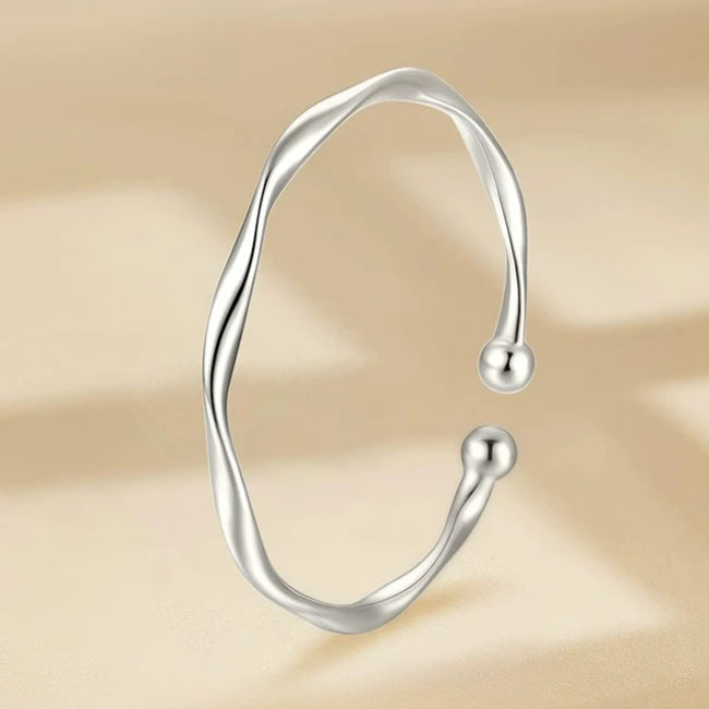 A silver bell bangle bracelet for women shown against a light background.