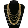 Gold stainless steel Cuban link necklace displayed on a black display stand.
