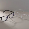 A pair of vintage square anti-blue light eyeglasses with black frames and blue lenses resting on a light surface.