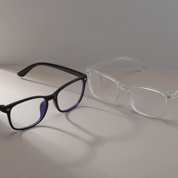 A pair of vintage square anti-blue light eyeglasses with black frames and blue lenses resting on a light surface.