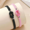 Two beaded bracelets, one black and one pink, are displayed on a wrist.