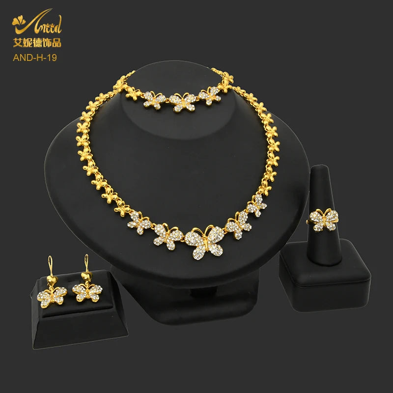 A gold heart crystal necklace and matching earrings set displayed on a black stand.