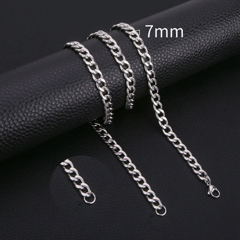 A set of silver stainless steel Cuban link necklaces of varying lengths displayed on a black fabric background.
