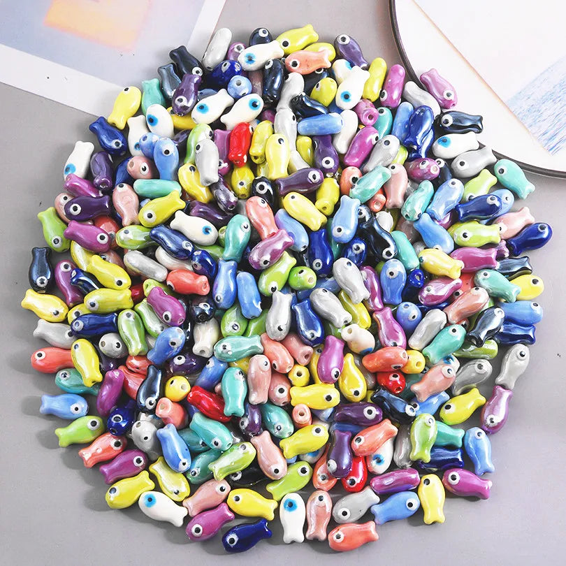 A large assortment of colorful ceramic fish charms used for DIY jewelry making