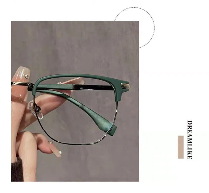 Eine Hand hält eine grüne Anti-Blaulicht-Lesebrille mit schwarzen Rahmen vor einem grauen Hintergrund.