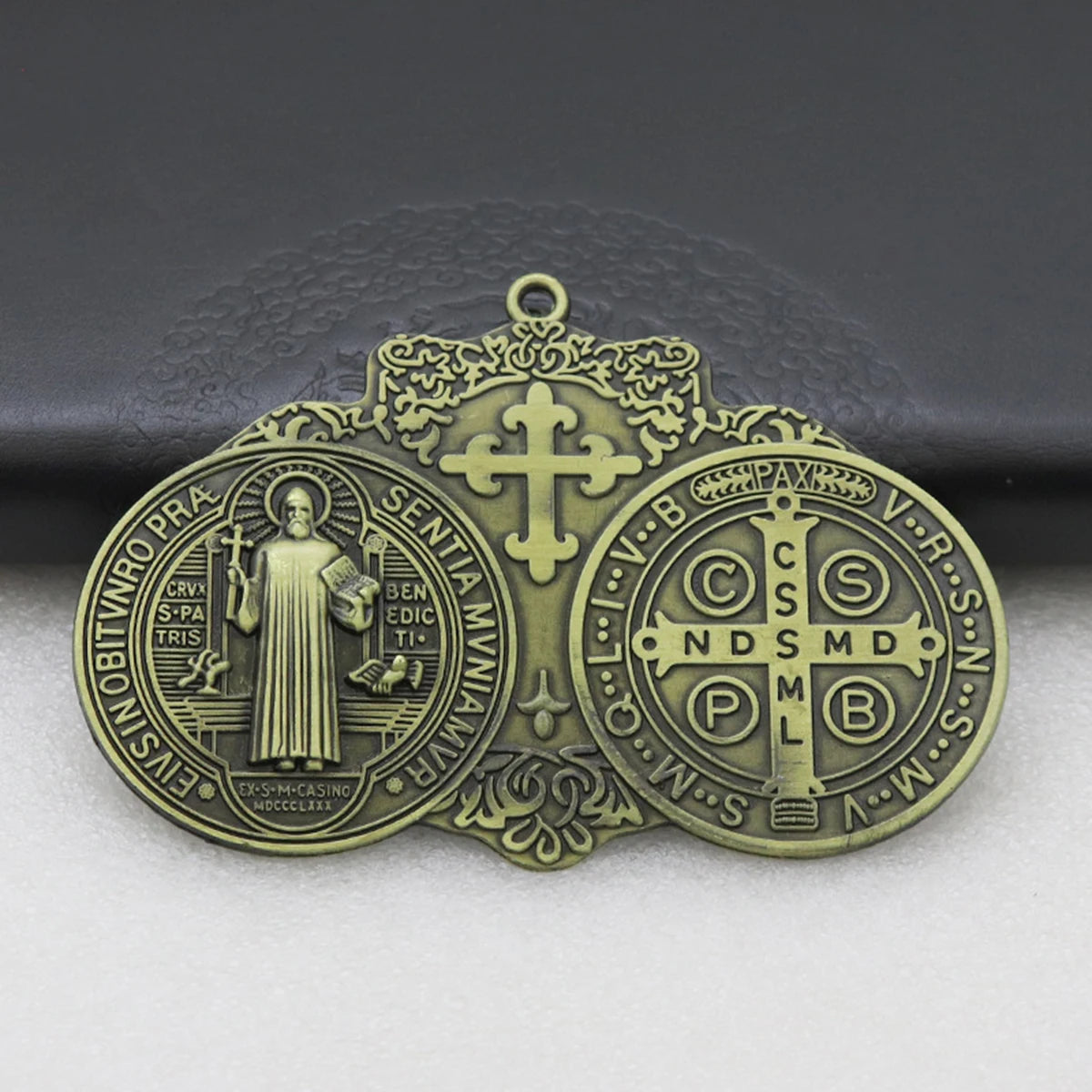A round bronze medal featuring a cross and religious symbols, designed for wall decor.