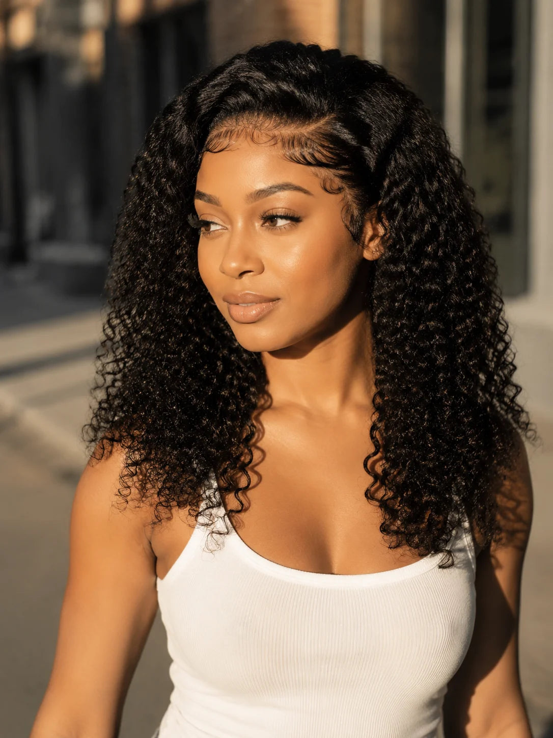 A woman modeling a natural Jerry curl lace front wig in a white tank top.