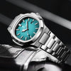 A silver luxury quartz wristwatch with a turquoise dial and luminous hands is shown on a dark background.