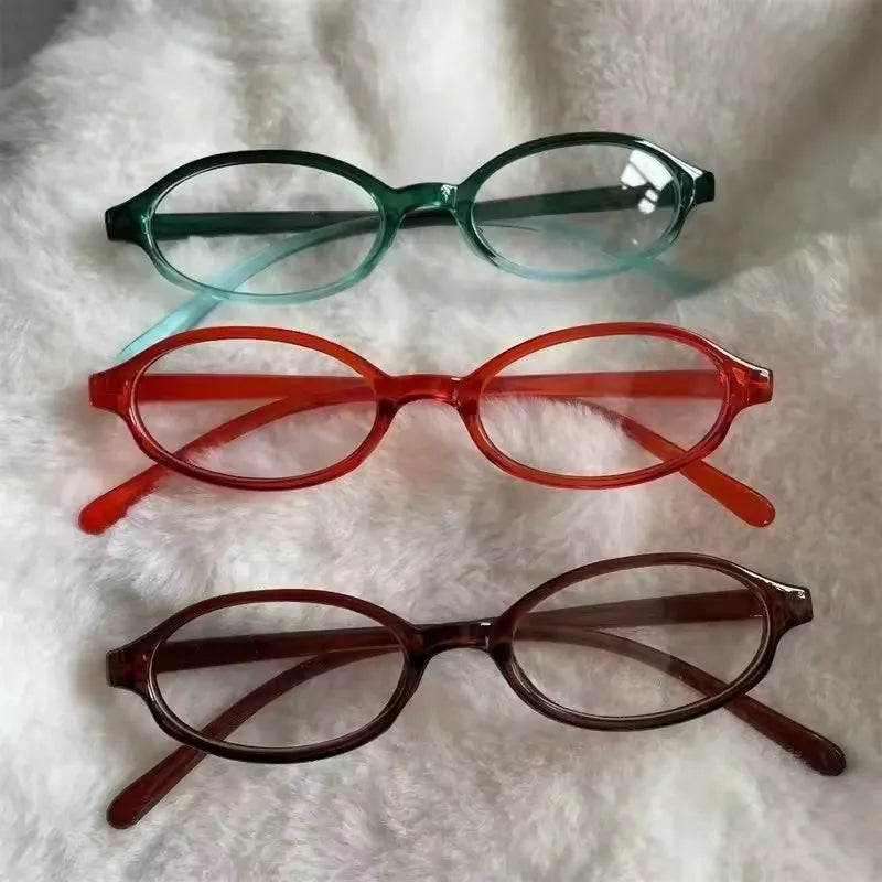 Un ensemble de trois lunettes de mode ovales rétro Y2K vert, orange et marron sur une surface blanche et duveteuse.