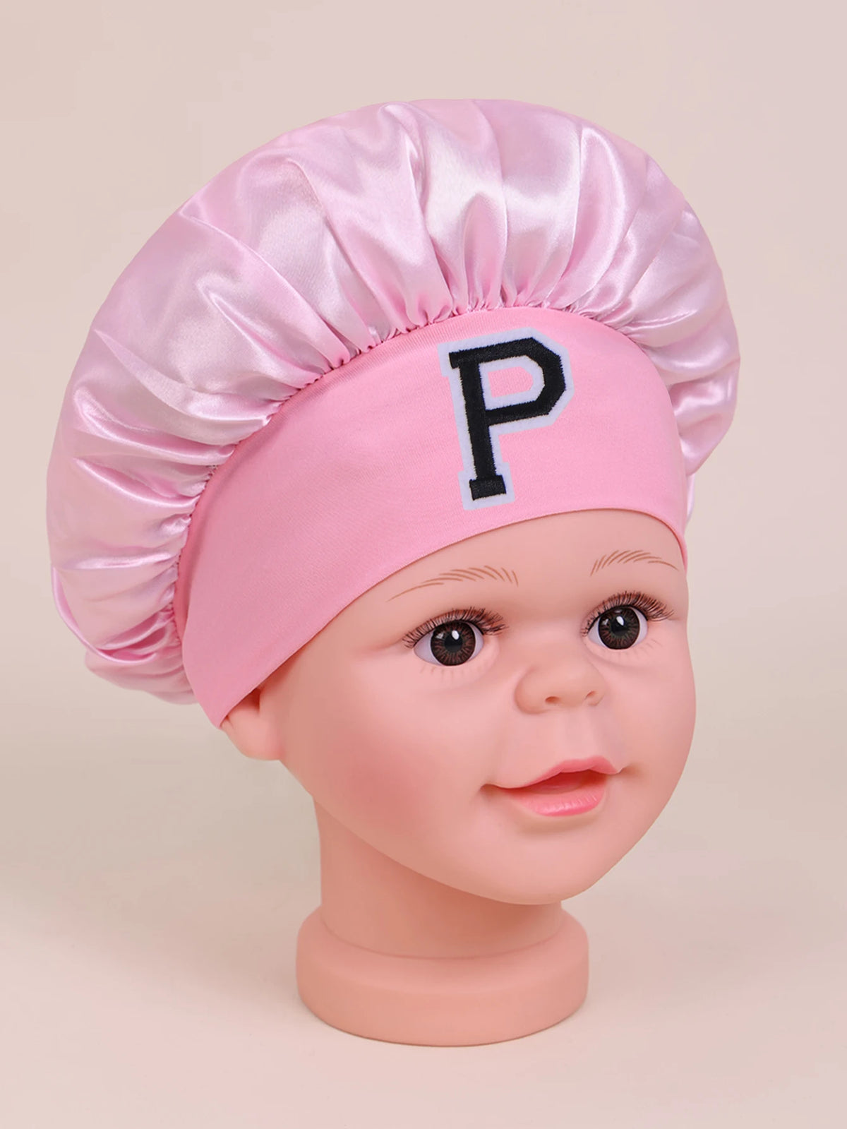 Pink satin sleep cap with a chef's hat style and a letter P embroidered on the front