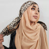 Eine Frau trägt einen beige Hijab mit Leopardenmuster und schwarzer Kleidung.