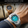 A close-up of a silver luxury quartz wristwatch with a blue luminous dial worn on a wrist.