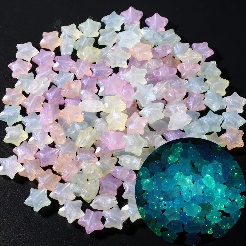 A collection of iridescent glow-in-the-dark acrylic beads in pastel pinks, whites, and yellows next to a sphere of blue-green