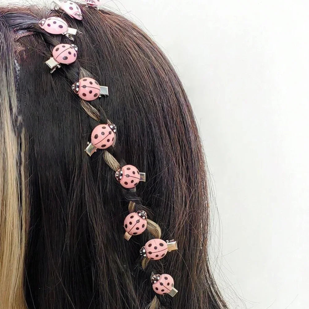 A set of ten pink ladybug hair clips adorning a dark brown hairstyle.