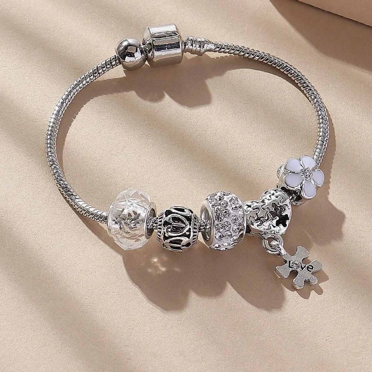 Silver beaded bracelet set featuring various charms including a cylinder, flower, and a love symbol.