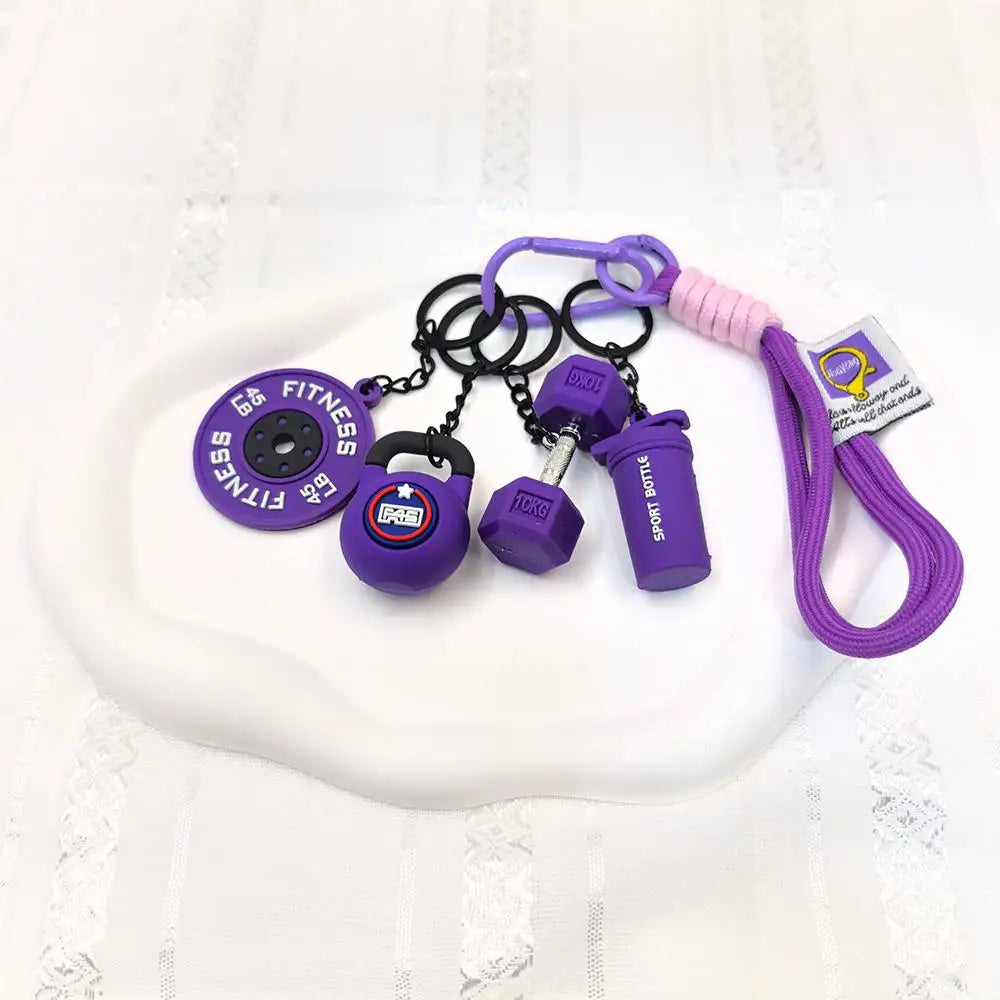 A set of five purple fitness keychains and weightlifting accessories including a bottle and weights displayed on a white plat