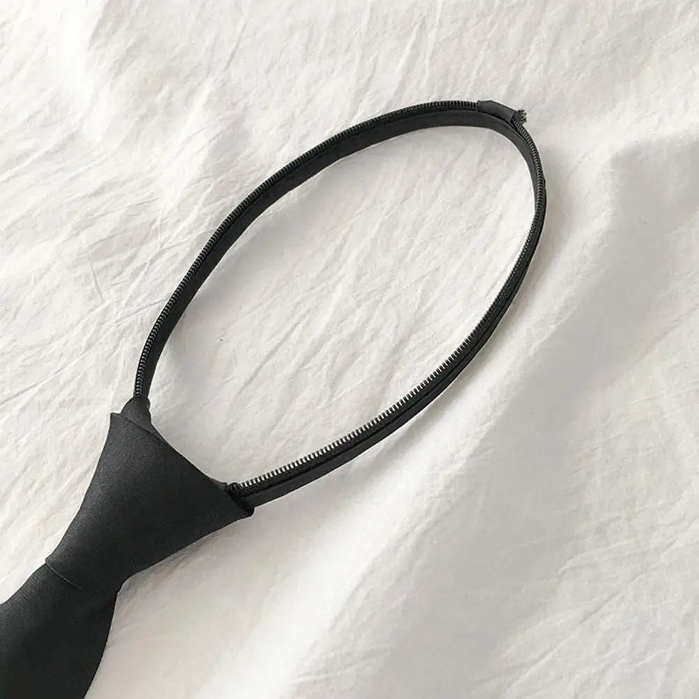 A black clip-on tie is shown against a white background.