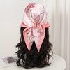 Pink floral silk scarf tied in a bow worn on a woman's dark hair.