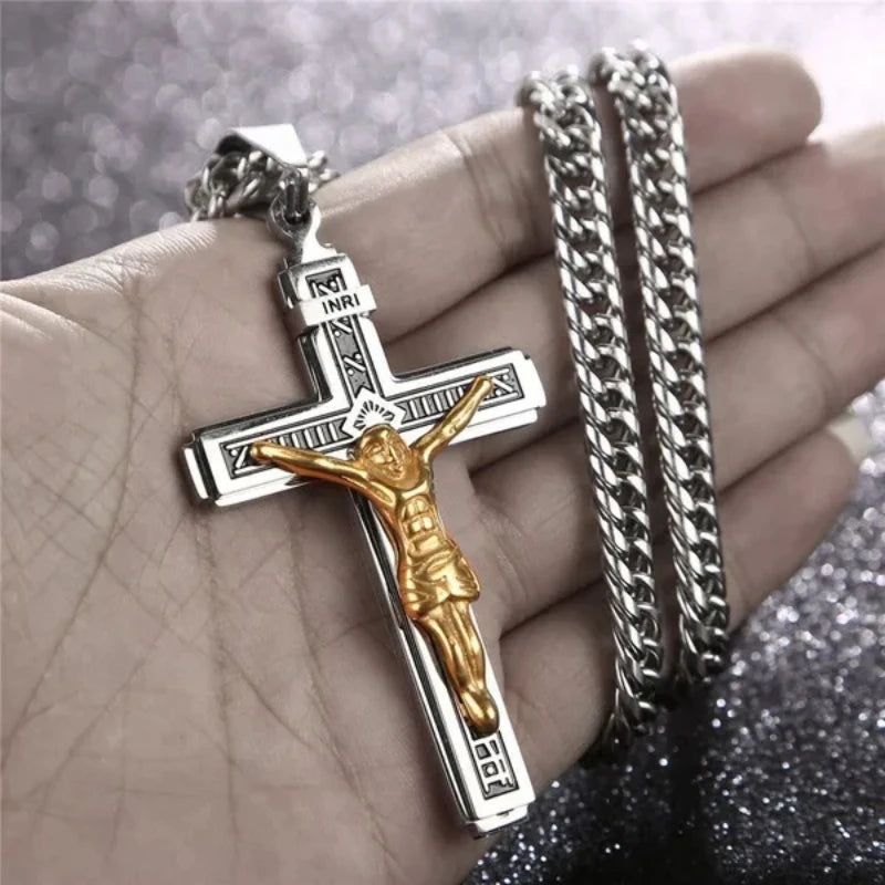 Collar de cruz de Jesús chapado en oro con cadena texturizada sostenido en la mano de una persona.