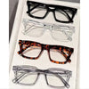 A collection of five pairs of reading glasses in various styles and colors displayed on a white surface.