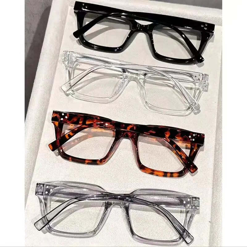 A collection of five pairs of reading glasses in various styles and colors displayed on a white surface.