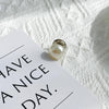 A close-up of a pearl button set resting on a white card against a textured white background.