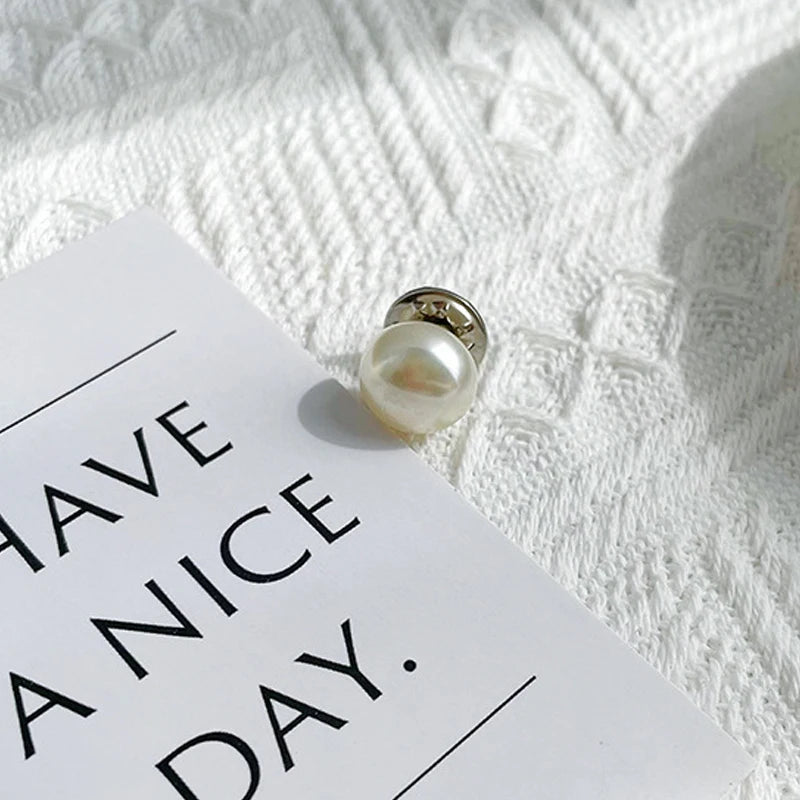 A close-up of a pearl button set resting on a white card against a textured white background.