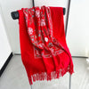 A vibrant red luxury floral scarf with white snowflake patterns displayed on a hanger.