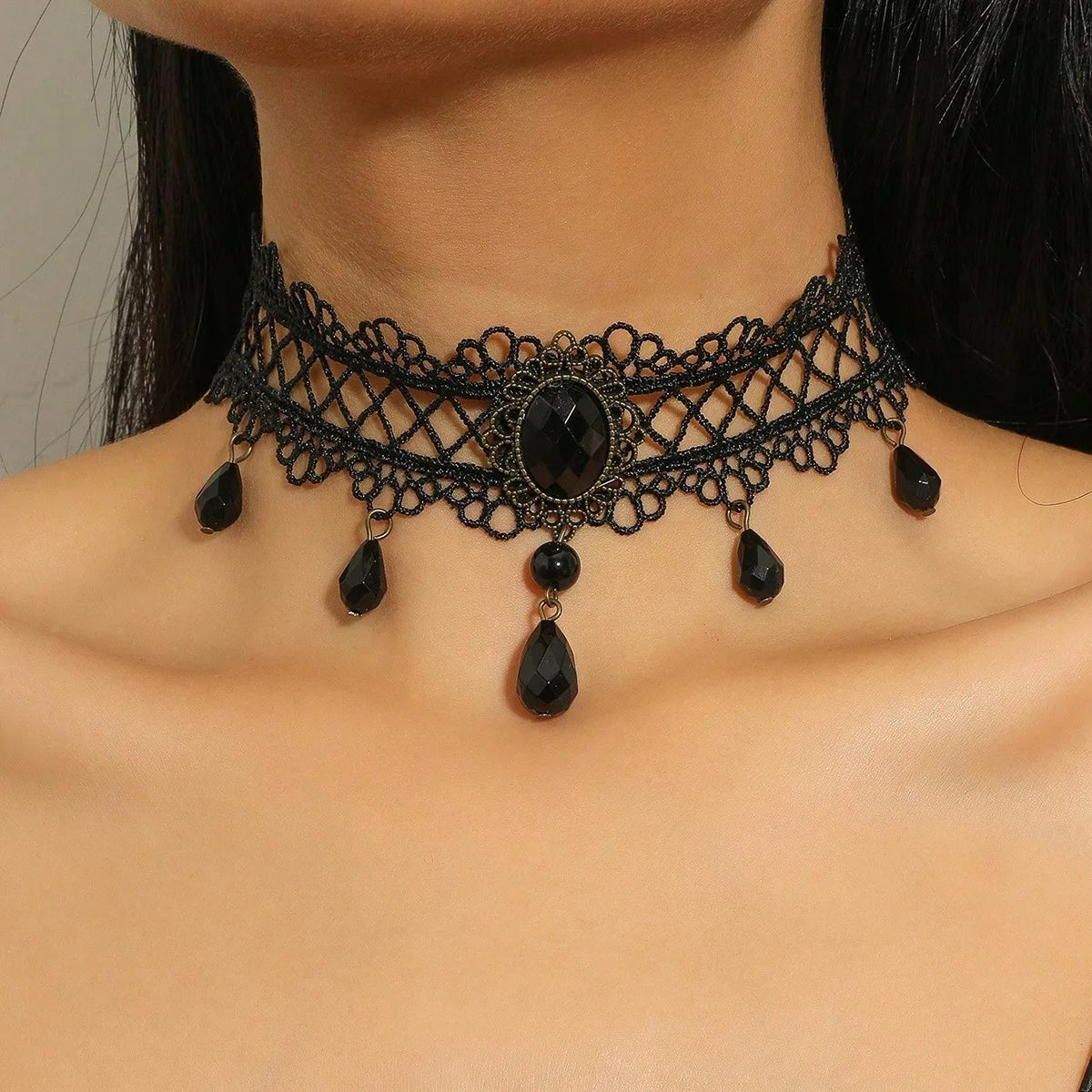 A black lace choker necklace featuring a central dark stone surrounded by intricate netting and dangling teardrop beads.