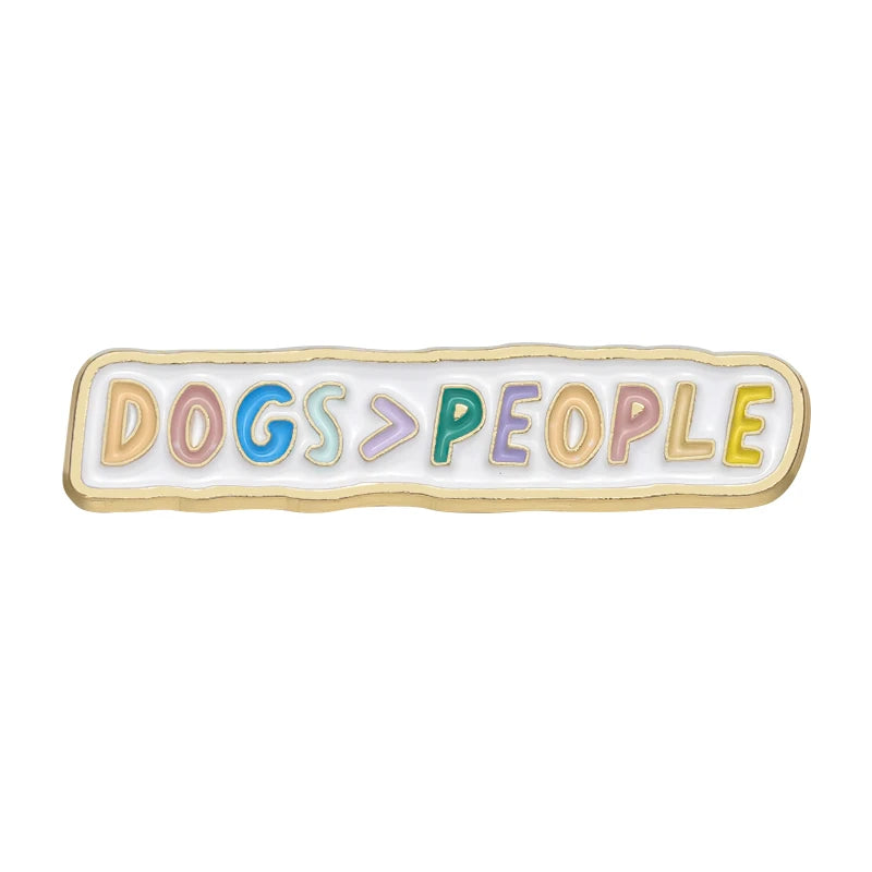 An enamel pin featuring the text DOGS > PEOPLE in pastel colored lettering.