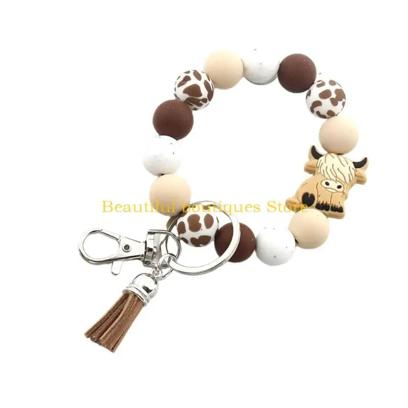 A silicone wristlet keychain featuring a pattern of beige and white Highland cow shapes.