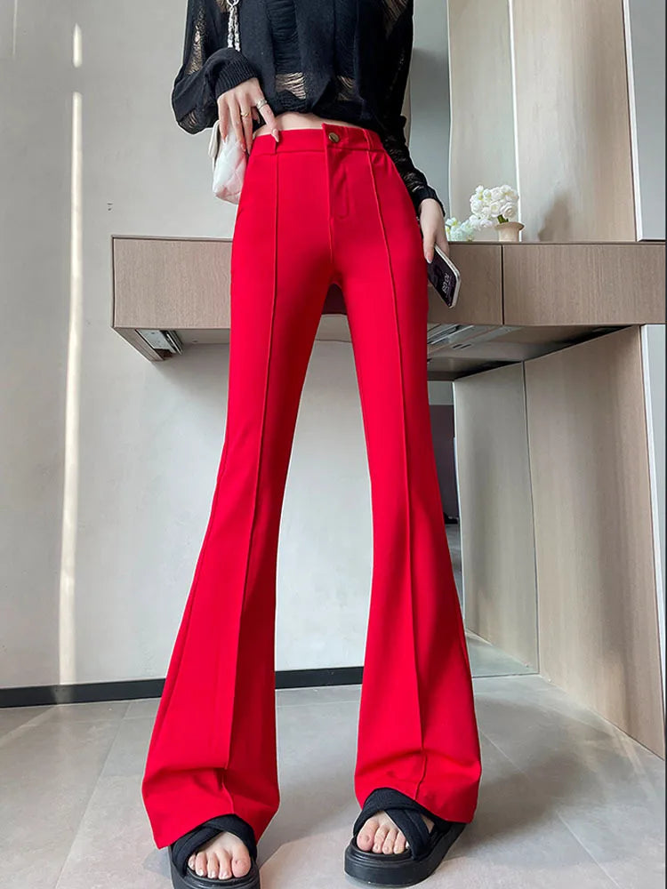 A woman models high-waist red flare skinny pants paired with a black top and black sandals.