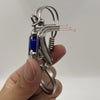 Un porte-clés mécanique en acier inoxydable avec une perle bleue et un fil enroulé tenu dans une main.