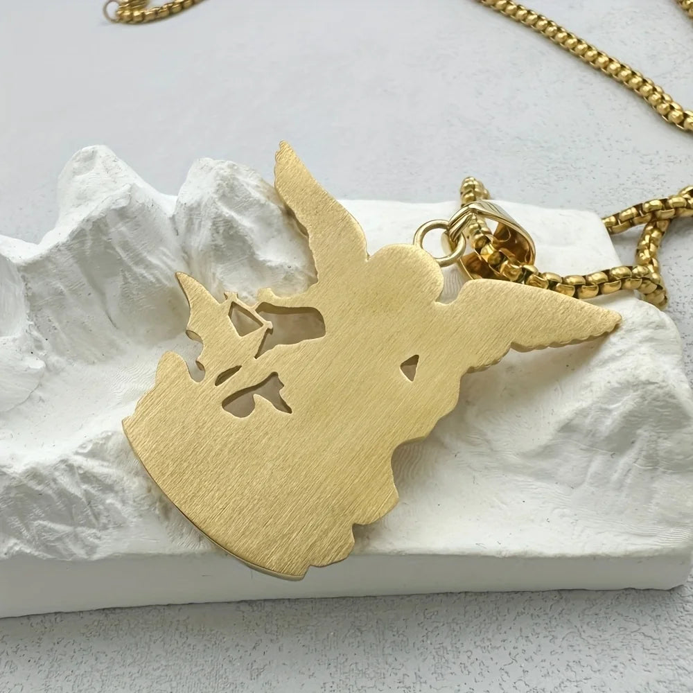 Un pendentif croix en acier inoxydable ton or affiché sur une surface de roche blanche.