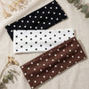 Trois bandeaux de sport noirs, blancs et marrons à pois présentés sur un fond de tissu clair.