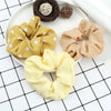 A display of three colorful knitted hair scrunchie headbands on a white plate.