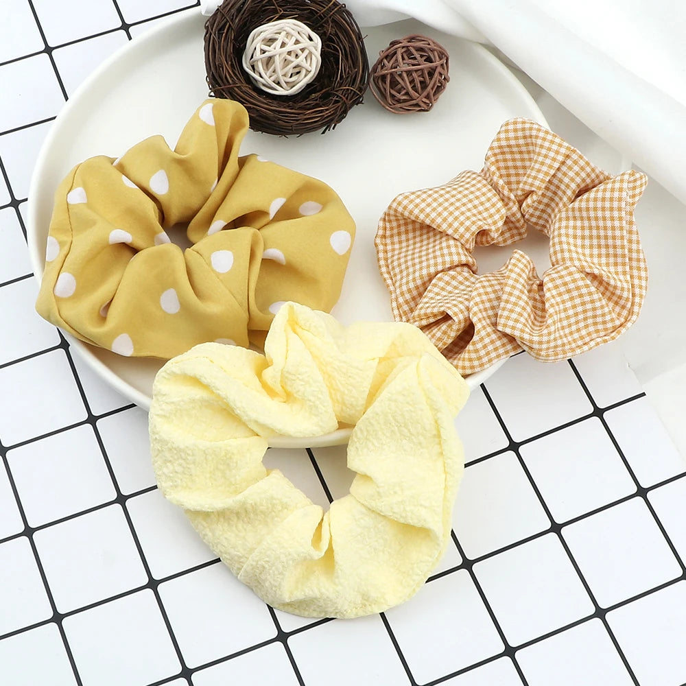 A display of three colorful knitted hair scrunchie headbands on a white plate.