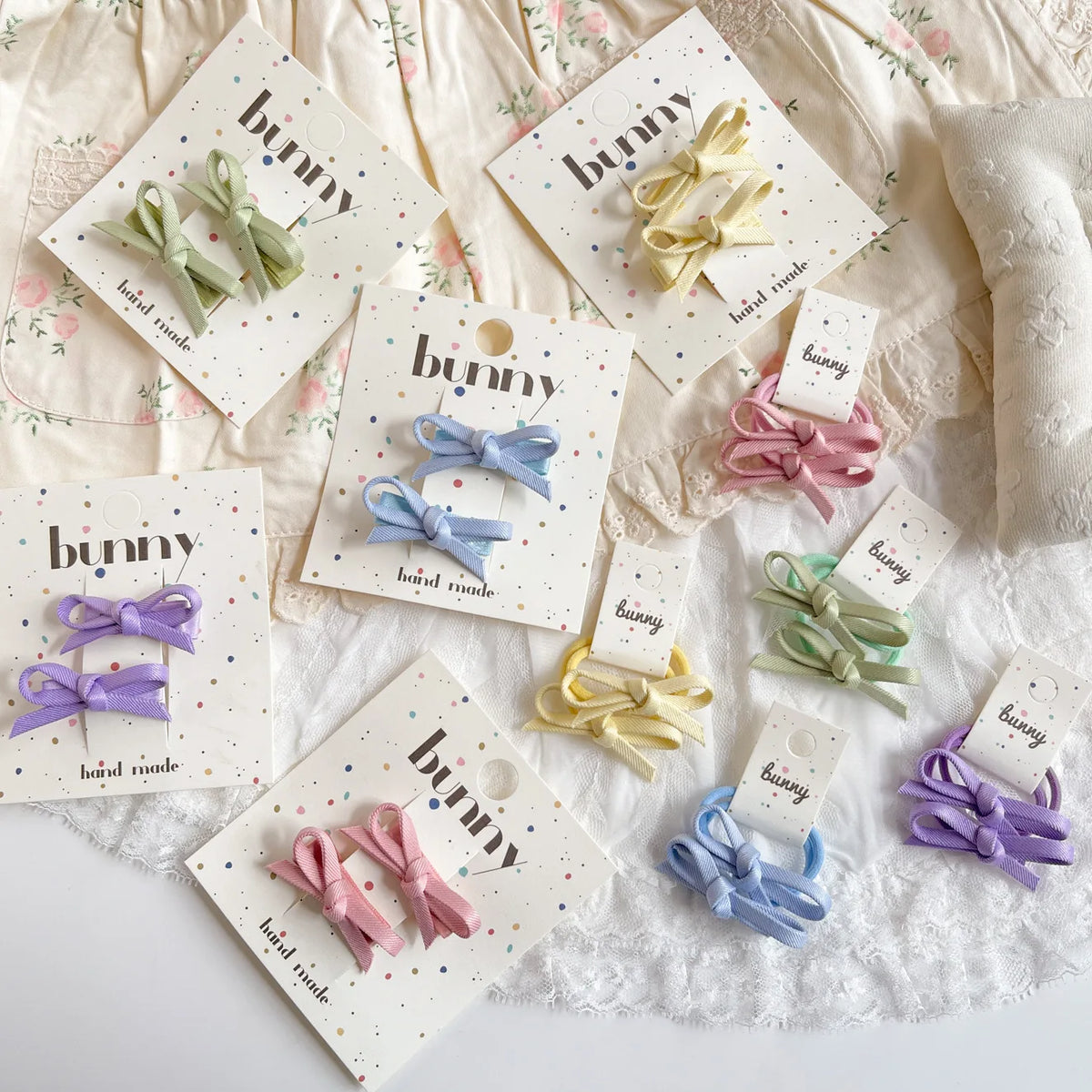 Collection de pinces à cheveux en nœud fait main de couleurs pastel comme rose, violet et vert menthe sur du papier blanc