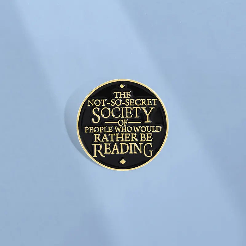 A round lapel pin featuring the text The Not-So-Secret Society of People Who Would Rather Be Reading