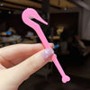 A hand holds a pink hair elastic and rubber band remover tool with a curved, hook-like shape.