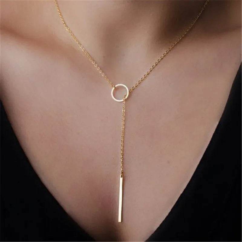 Un collier délicat minimaliste en perles d'or porté autour du cou.
