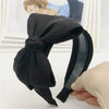 Black chic wide bow headband for women shown against a white background.