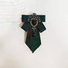 A dark green tie with black diamond embellishments and a decorative brooch pin.