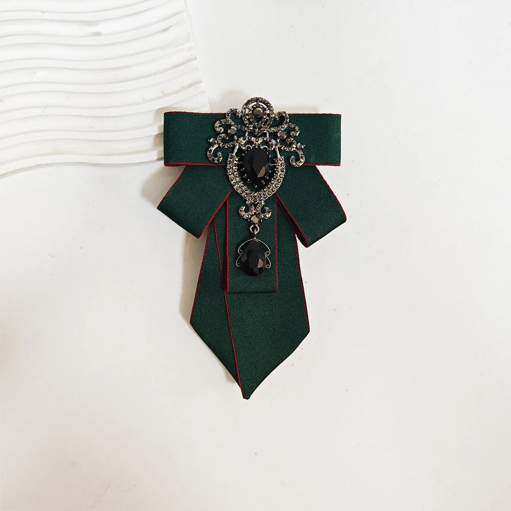 A dark green tie with black diamond embellishments and a decorative brooch pin.