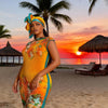 A plus size model wearing a vibrant yellow and orange African silk printed two-piece set on a beach at sunset.